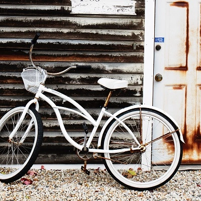 an old, white bike leaning against the wall of a wooden house